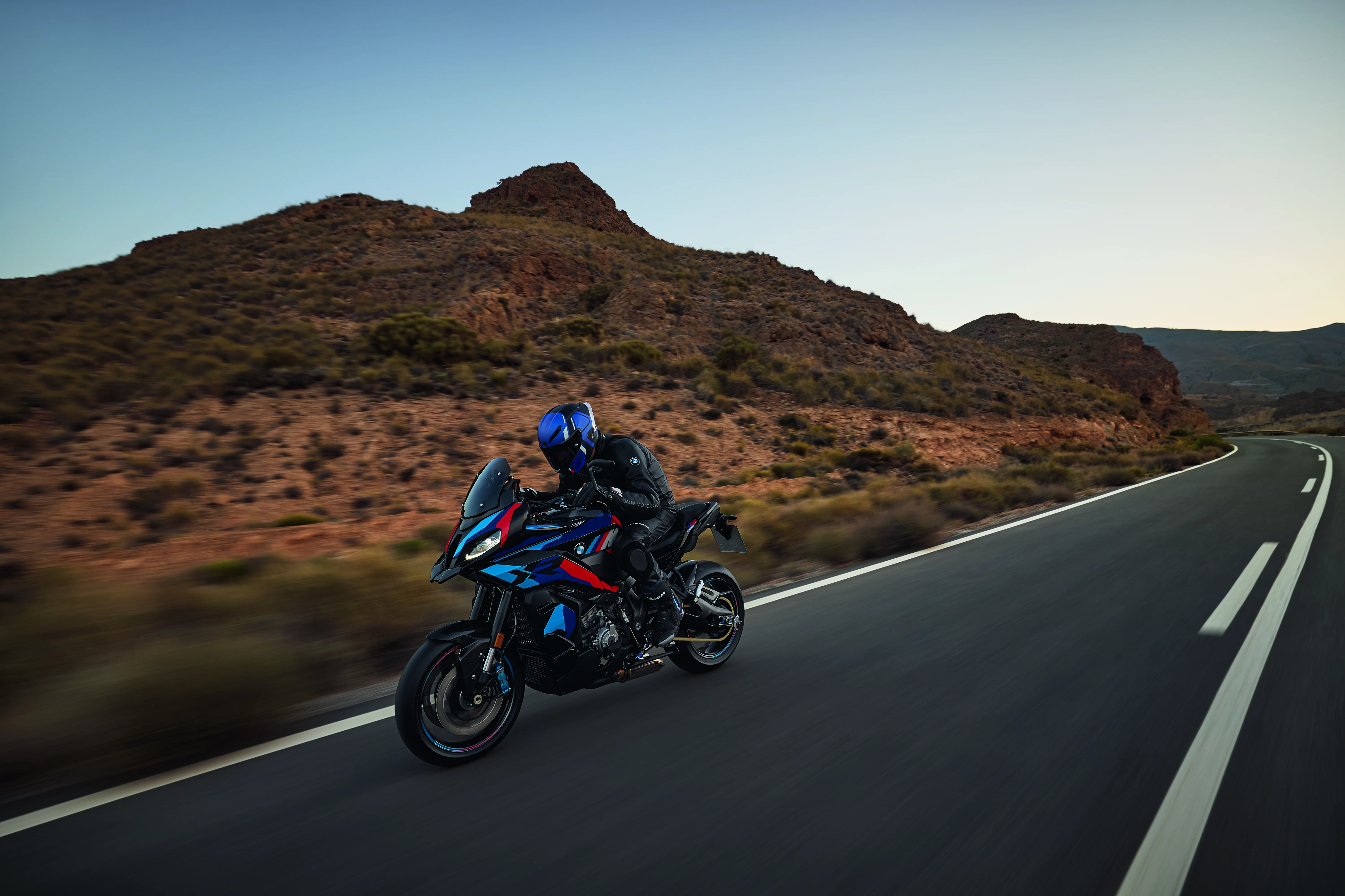 BMW M 1000 XR riding on a desert road with mountains and open sky