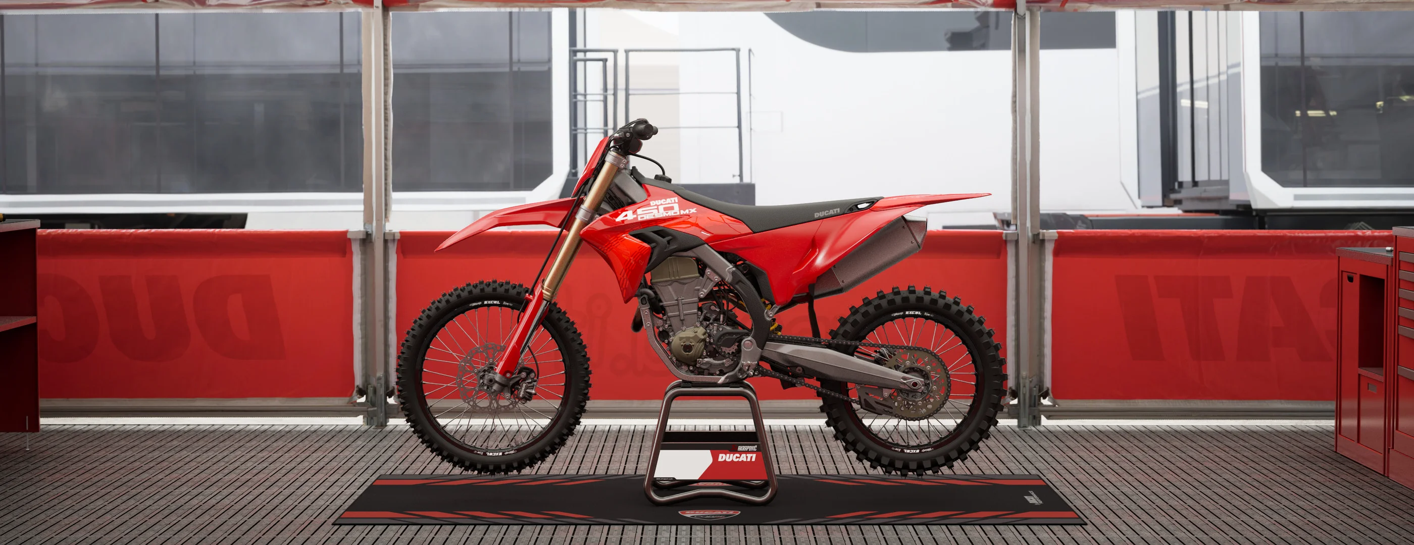 2026 Ducati Desmo450 MX red left-side profile in a race-pit workshop setting