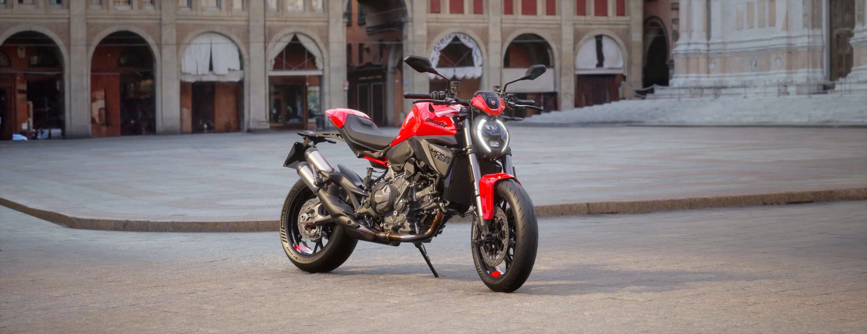 2026 Ducati Monster+ red front three-quarter view in an urban setting